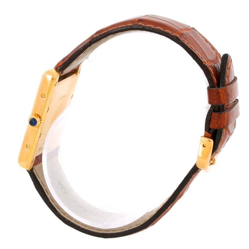 This image shows a side view of the Tank Louis watch by Cartier, highlighting the gold case, crown with blue tip, and brown leather strap.