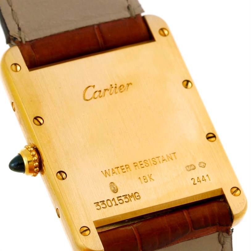 The image shows the back case of a Cartier Tank Louis W1529756 Men
s Silver Dial W1529756 Men
s Silver Dial watch, highlighting its engravings and 18K gold feature.