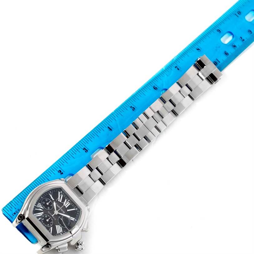 This image shows the Cartier Roadster W62020X6 Men
s Stainless Steel Black Dial W62020X6 Men
s Stainless Steel Black Dial watch at a diagonal angle with a blue ruler beside it for measurement.