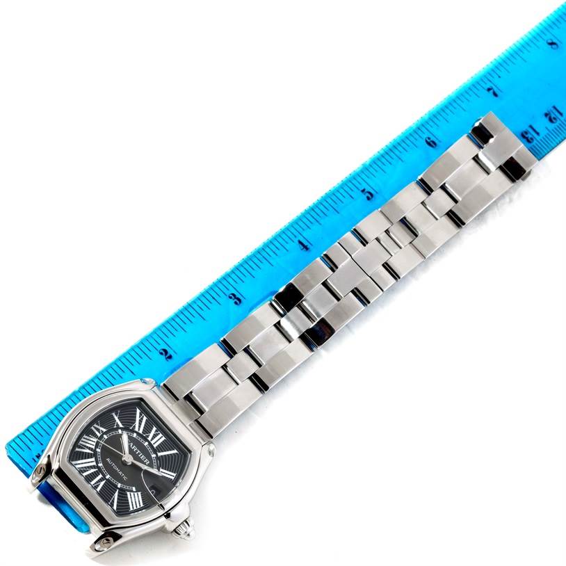 A Cartier Roadster W62041V3 Men's Stainless Steel Black Dial W62041V3 Men's Stainless Steel Black Dial watch is displayed at an angle, showcasing its face, crown, and bracelet with a ruler for scale.