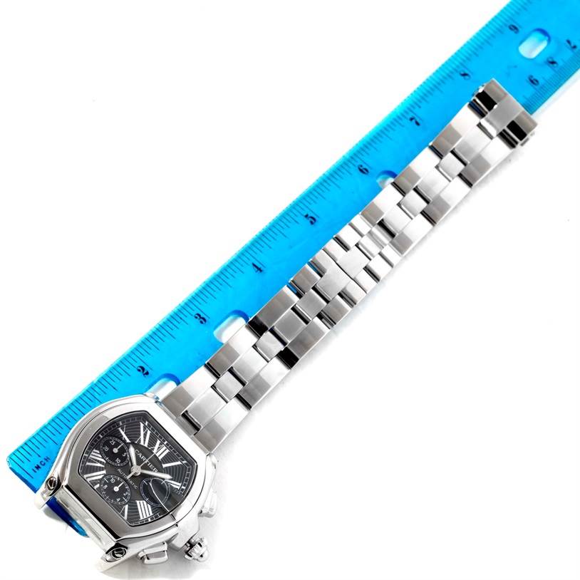 This image shows a Cartier Roadster W62020X6 Men's Stainless Steel Black Dial W62020X6 Men's Stainless Steel Black Dial watch laid flat with its face and entire metal bracelet visible, next to a ruler for scale.