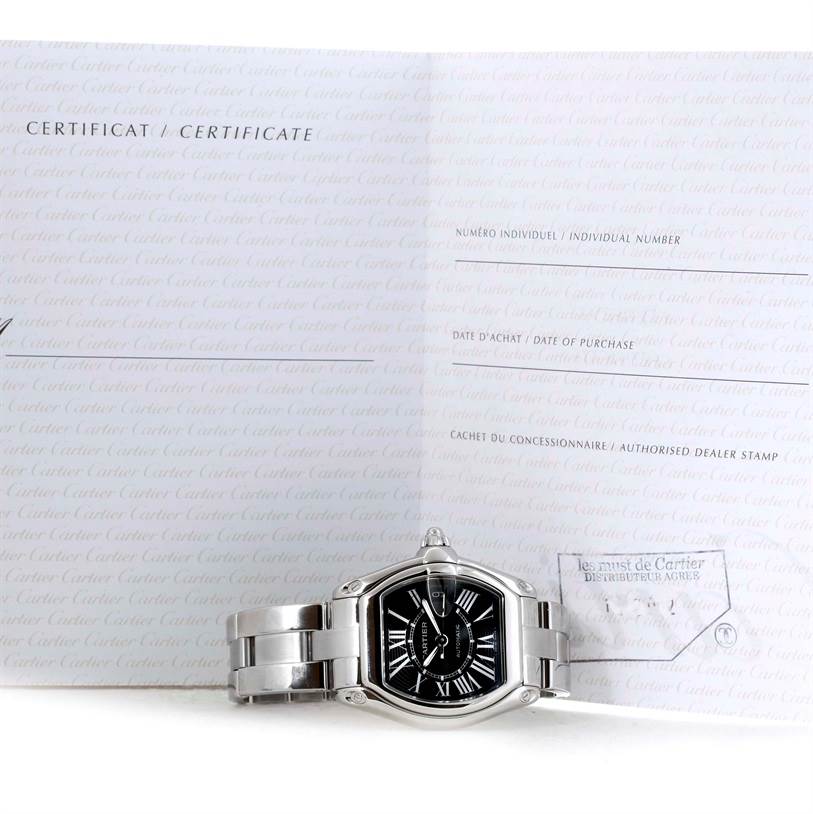 The Cartier Roadster W62041V3 Men's Stainless Steel Black Dial W62041V3 Men's Stainless Steel Black Dial watch is displayed with a certificate behind it, showing its front and bracelet.