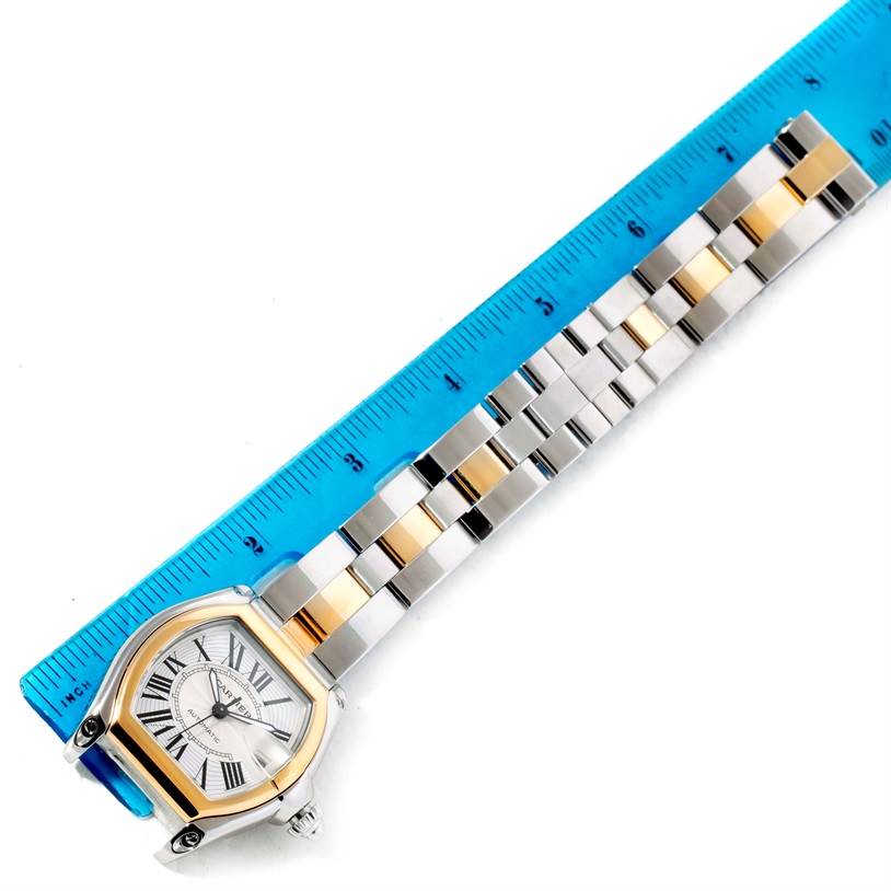 The Cartier Roadster W62031Y4 Men's Steel and Gold (two tone) Silver Dial W62031Y4 Men's Steel and Gold (two tone) Silver Dial watch is shown from an overhead angle, displaying the face, bezel, and a portion of the band, with a ruler beside it.