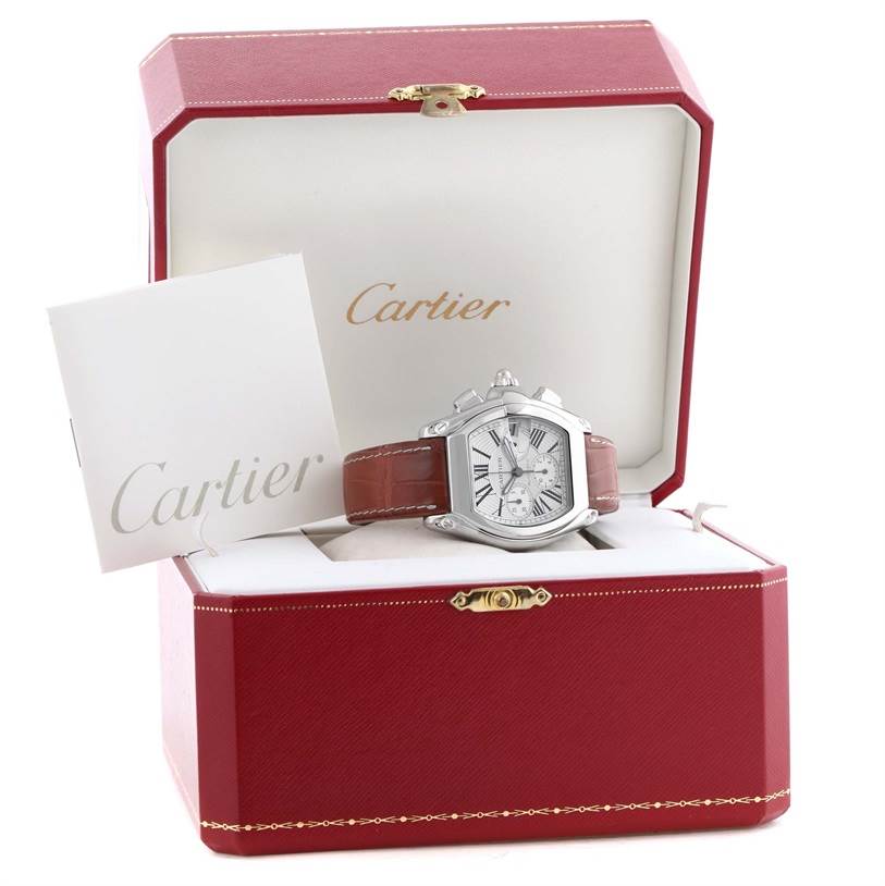 The Cartier Roadster W62019X6 Men's Stainless Steel Silver Dial W62019X6 Men's Stainless Steel Silver Dial watch is displayed front-on in an open red Cartier box, accompanied by a Cartier booklet.