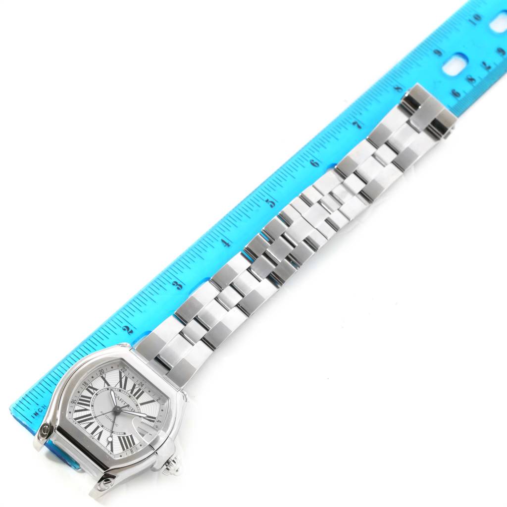The image shows a Cartier Roadster W62032X6 Men
s Stainless Steel Silver Dial W62032X6 Men
s Stainless Steel Silver Dial watch face and bracelet laid flat next to a blue ruler.