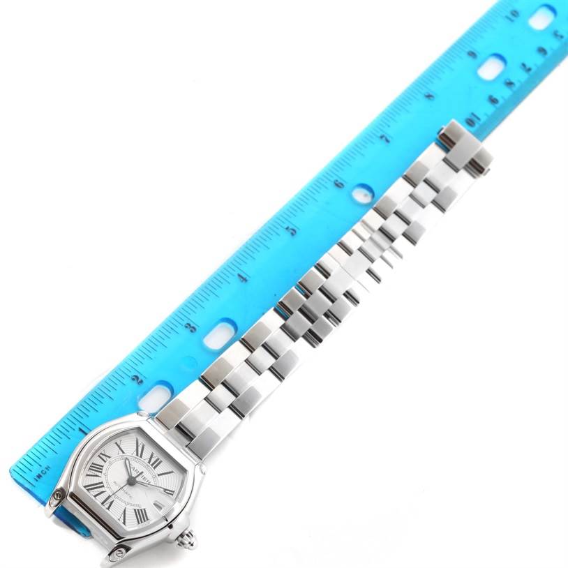 The image shows the Cartier Roadster W62025V3 Men's Stainless Steel Silver Dial W62025V3 Men's Stainless Steel Silver Dial watch and its metal bracelet band placed alongside a blue ruler for size reference.