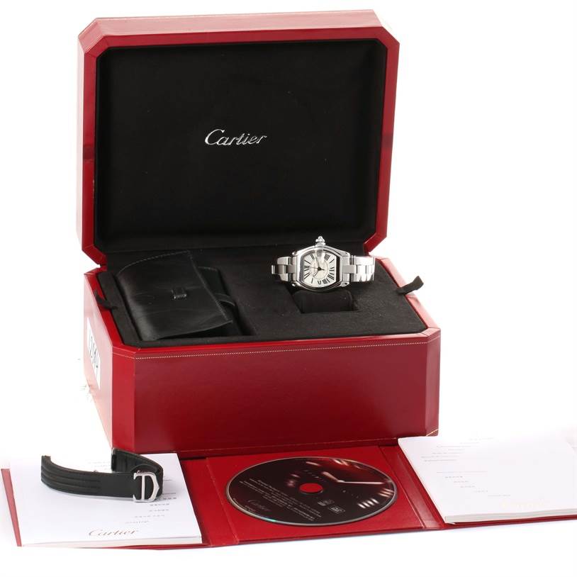 The Cartier Roadster W62025V3 Men's Stainless Steel Silver Dial W62025V3 Men's Stainless Steel Silver Dial watch is displayed in its box with accessories including an extra strap, a CD, and documentation.