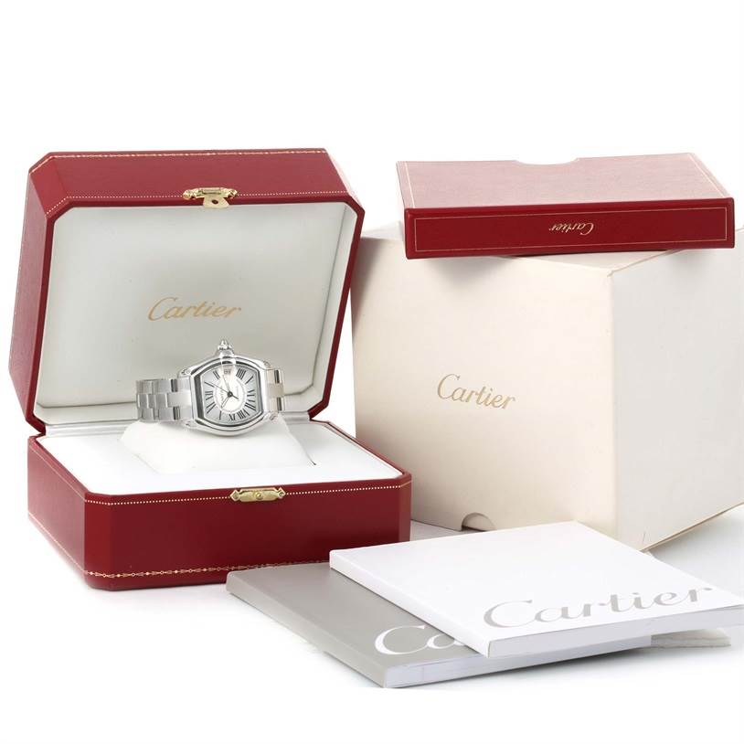 The Cartier Roadster W62025V3 Men's Stainless Steel Silver Dial W62025V3 Men's Stainless Steel Silver Dial watch is displayed open in its original red box, with additional packaging and booklets visible.