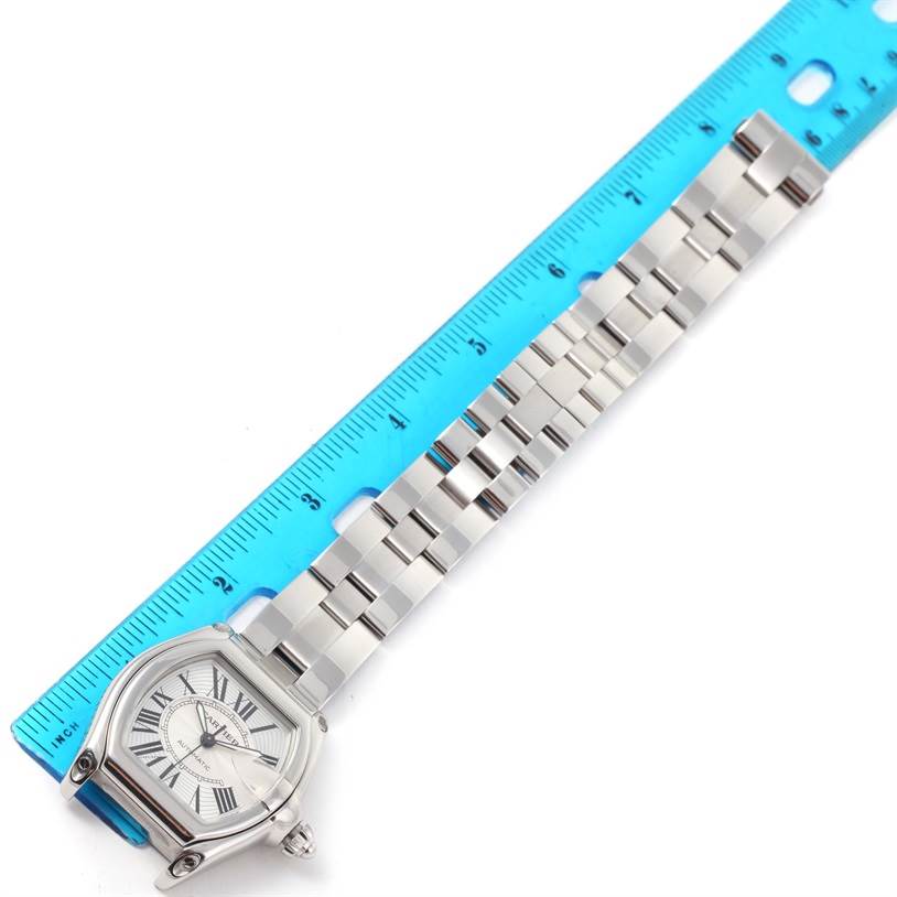 The Cartier Roadster W62025V3 Men
s Stainless Steel Silver Dial W62025V3 Men
s Stainless Steel Silver Dial watch is shown laid flat with the full bracelet and dial visible next to a blue ruler.
