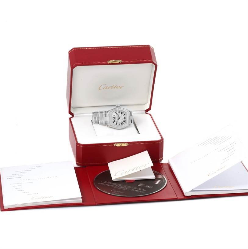 The image shows the Cartier Roadster W62025V3 Men
s Stainless Steel Silver Dial W62025V3 Men
s Stainless Steel Silver Dial watch in an open red box with accessories like documents and a CD.