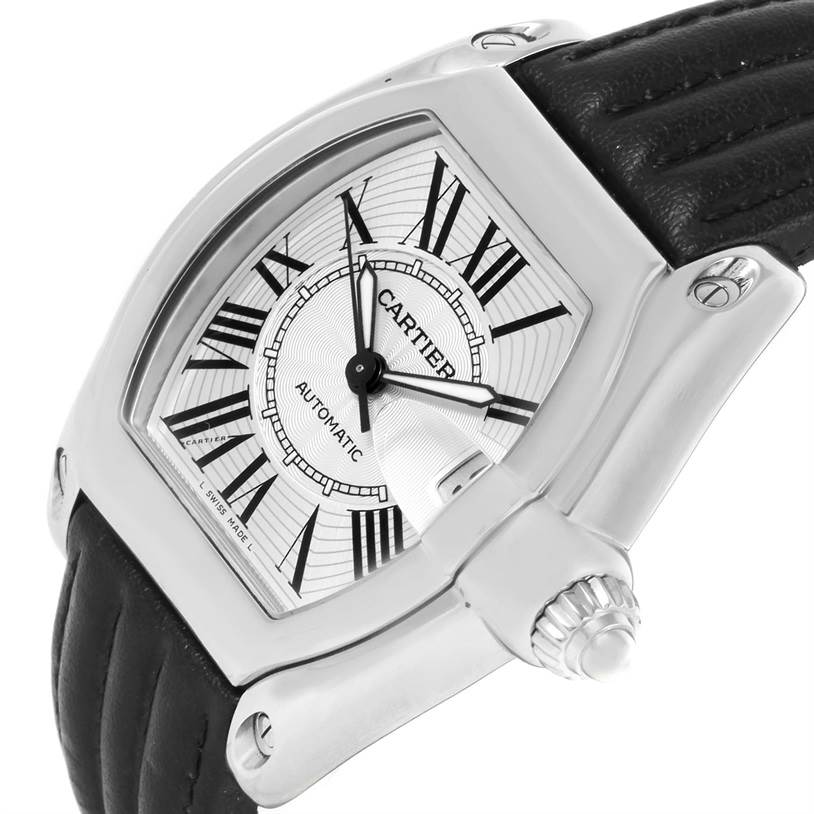 The image shows a close-up of a Cartier Roadster W62025V3 Men's Stainless Steel Silver Dial W62025V3 Men's Stainless Steel Silver Dial watch at an angle, highlighting its white dial, Roman numerals, and the crown.