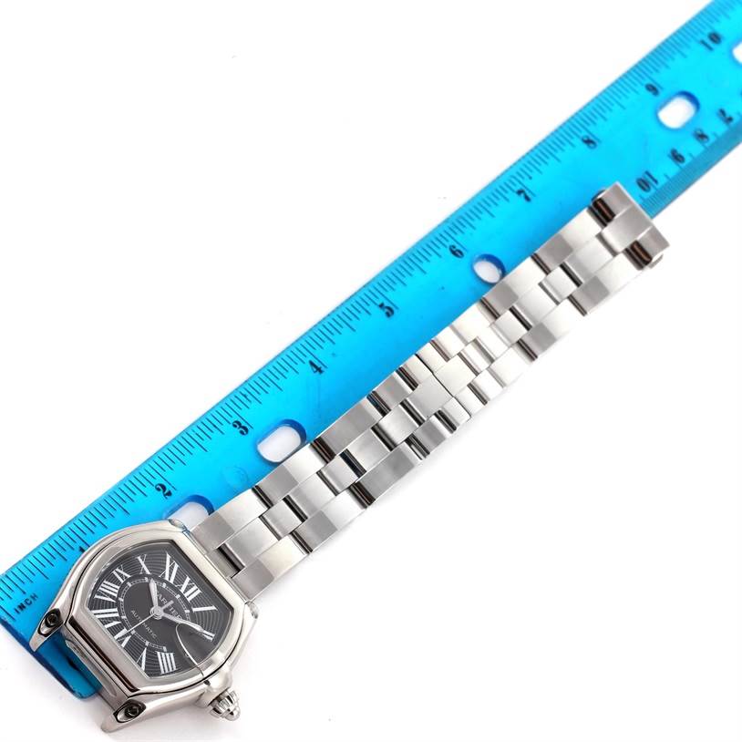 The image shows a Cartier Roadster W62041V3 Men
s Stainless Steel Black Dial W62041V3 Men
s Stainless Steel Black Dial watch laid flat next to a blue ruler, displaying the face and metal bracelet.