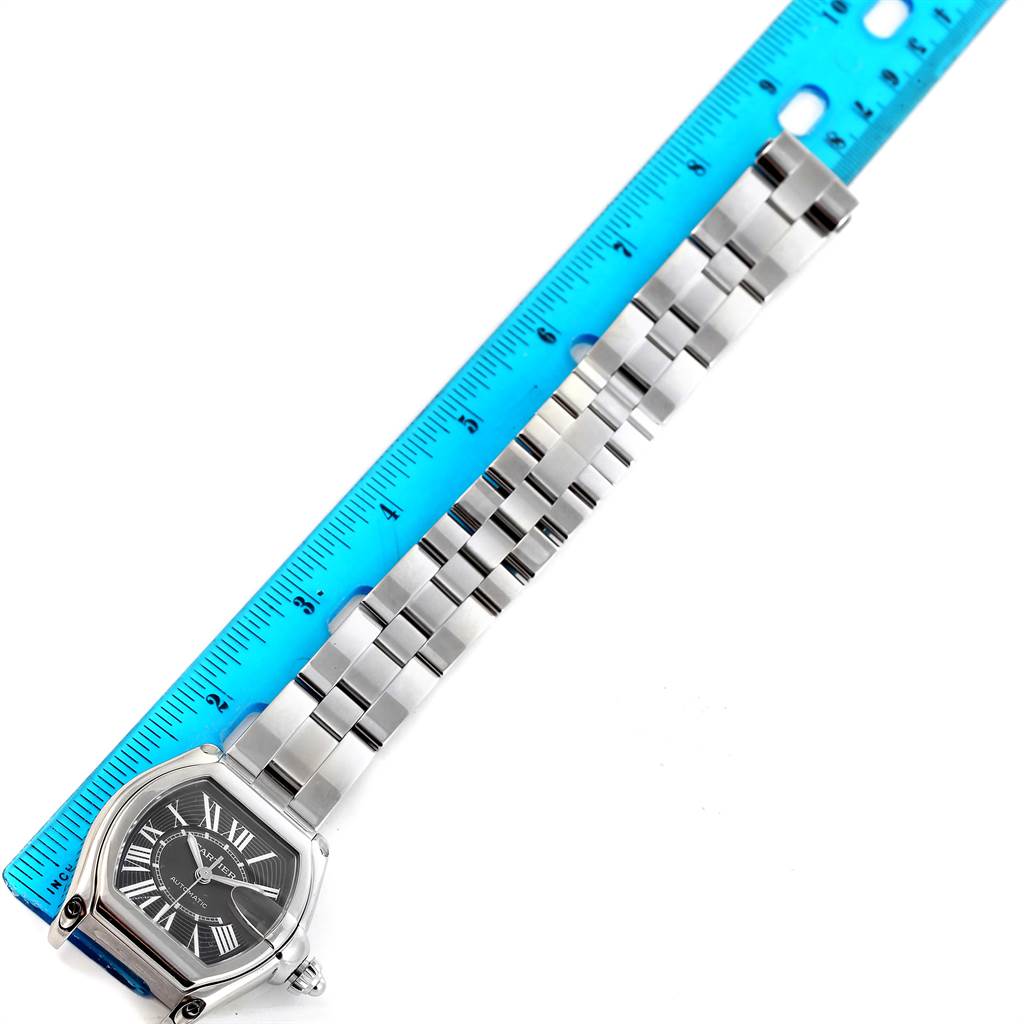 The image shows a Cartier Roadster W62041V3 Men's Stainless Steel Black Dial W62041V3 Men's Stainless Steel Black Dial watch laid flat next to a ruler, highlighting its face and metal bracelet.