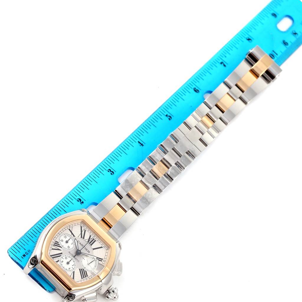 This image shows a Cartier Roadster W62027Z1 Men's Steel and Gold (two tone) Silver Dial W62027Z1 Men's Steel and Gold (two tone) Silver Dial watch, with its face and bracelet displayed next to a blue ruler for measurement.