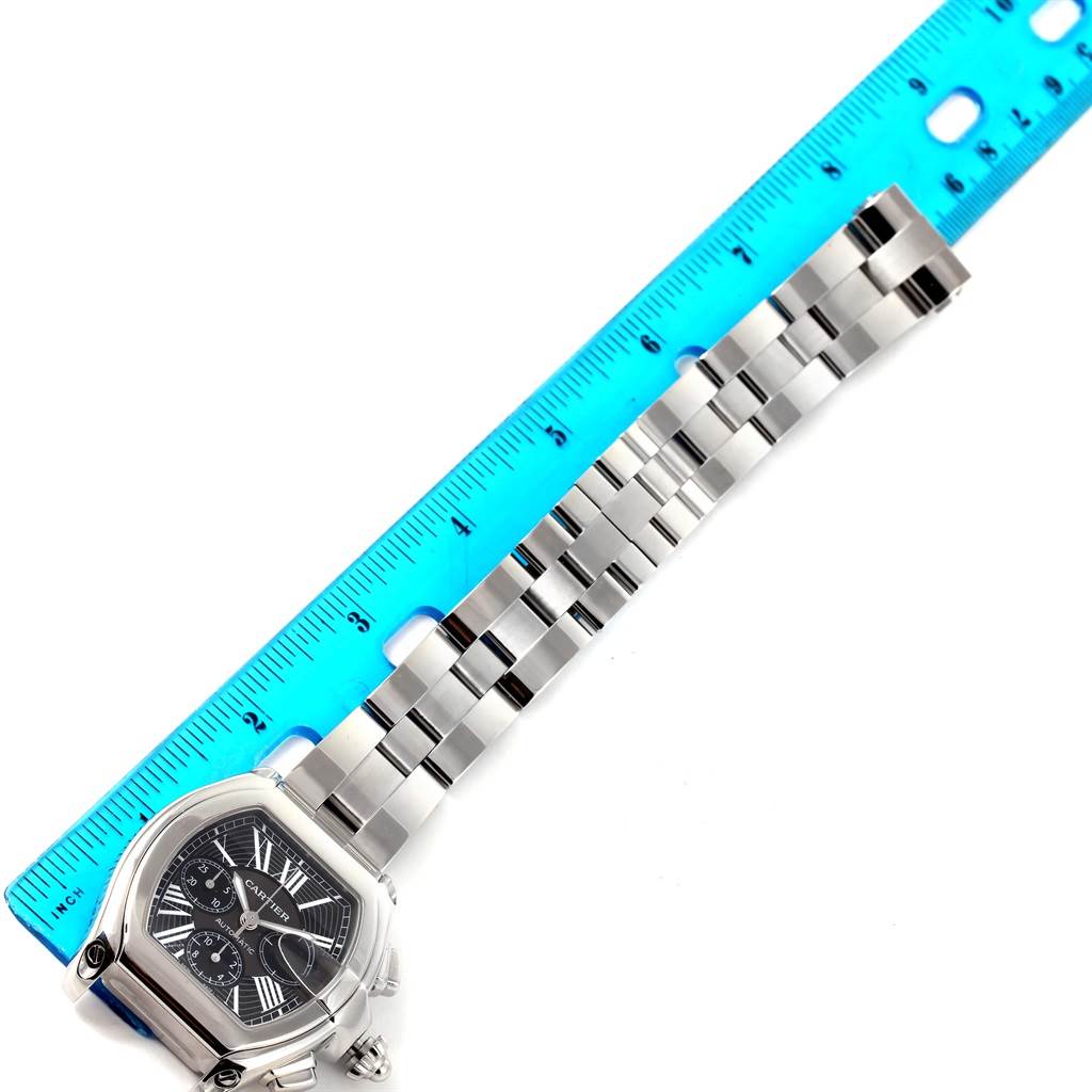 The image shows the Cartier Roadster W62020X6 Men
s Stainless Steel Black Dial W62020X6 Men
s Stainless Steel Black Dial watch face and bracelet, measured against a blue ruler.