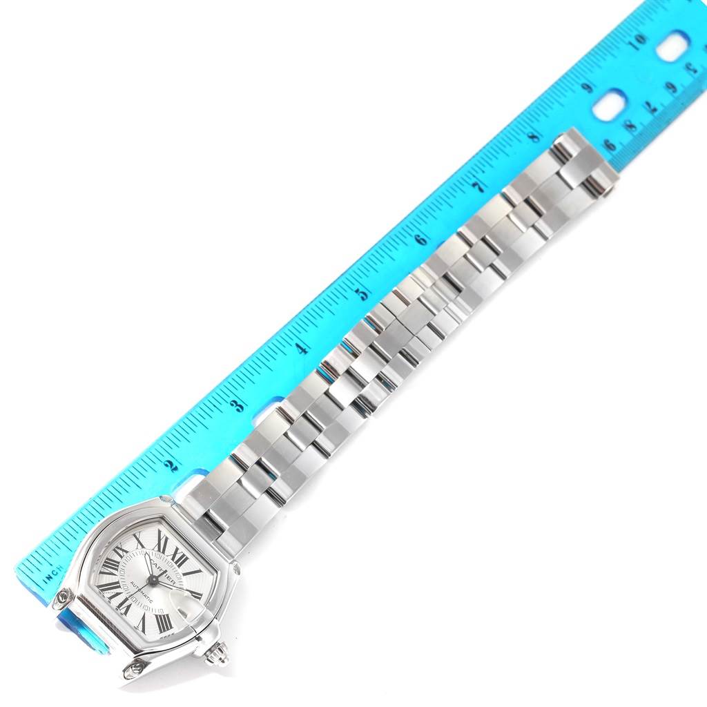 The image shows the Cartier Roadster W62025V3 Men
s Stainless Steel Silver Dial W62025V3 Men
s Stainless Steel Silver Dial watch laying flat, along with a ruler measuring the length of its metal bracelet.