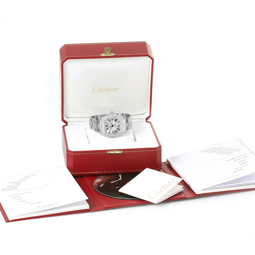 The Cartier Roadster W62025V3 Men
s Stainless Steel Silver Dial W62025V3 Men
s Stainless Steel Silver Dial watch is shown in an open red box from a front angle, along with its warranty papers and manual.