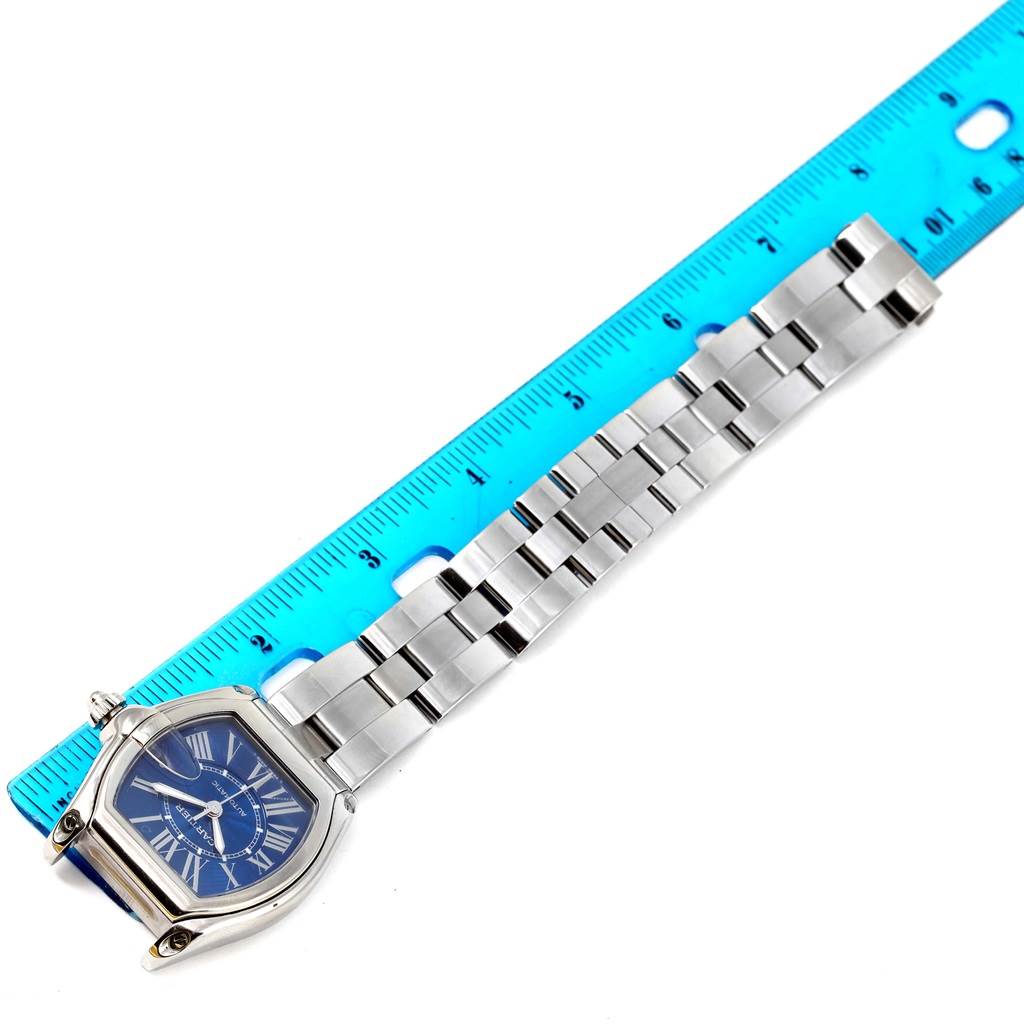 The Cartier Roadster W62048V3 Men
s Stainless Steel Blue Dial W62048V3 Men
s Stainless Steel Blue Dial watch is shown lying flat with its face and metal bracelet next to a blue ruler for scale.
