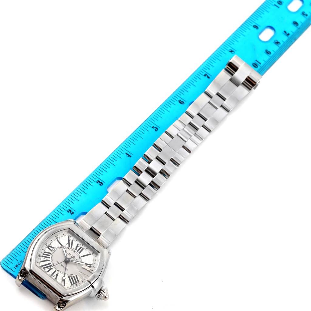 The Cartier Roadster W62032X6 Men's Stainless Steel Silver Dial W62032X6 Men's Stainless Steel Silver Dial watch is shown fully extended alongside a ruler, displaying its face, bracelet, and clasp.