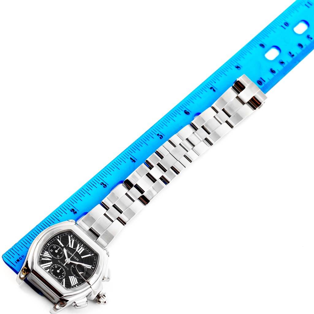 The image shows the Cartier Roadster W62020X6 Men
s Stainless Steel Black Dial W62020X6 Men
s Stainless Steel Black Dial watch face and metal bracelet measured against a blue ruler.
