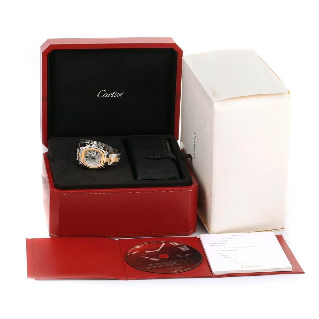 The Cartier Roadster W62027Z1 Men's Steel and Gold (two tone) Silver Dial W62027Z1 Men's Steel and Gold (two tone) Silver Dial watch is shown at a slight angle within its open red box, accompanied by a booklet, CD, and outer white box.