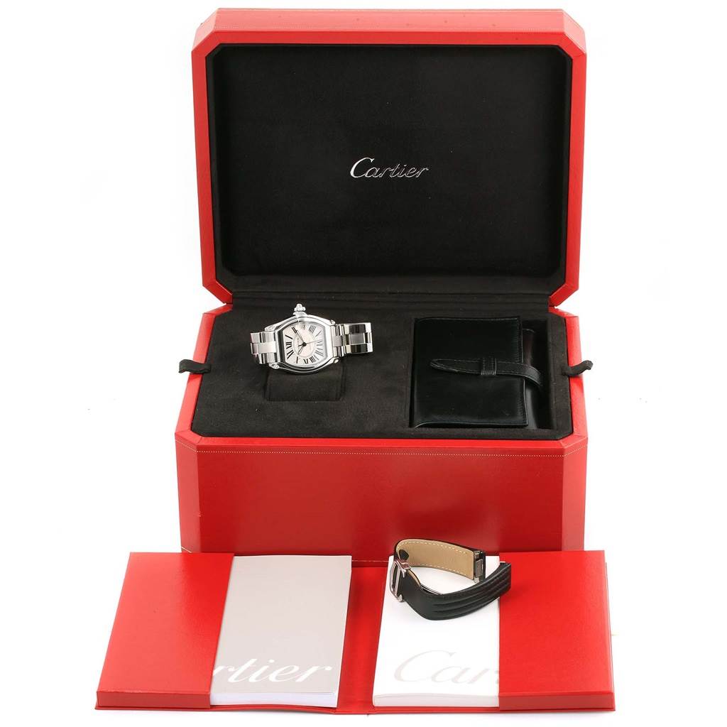 The image shows a Cartier Roadster W62025V3 Men
s Stainless Steel Silver Dial W62025V3 Men
s Stainless Steel Silver Dial watch in its case with additional leather straps and manuals, viewed from a slightly elevated angle.