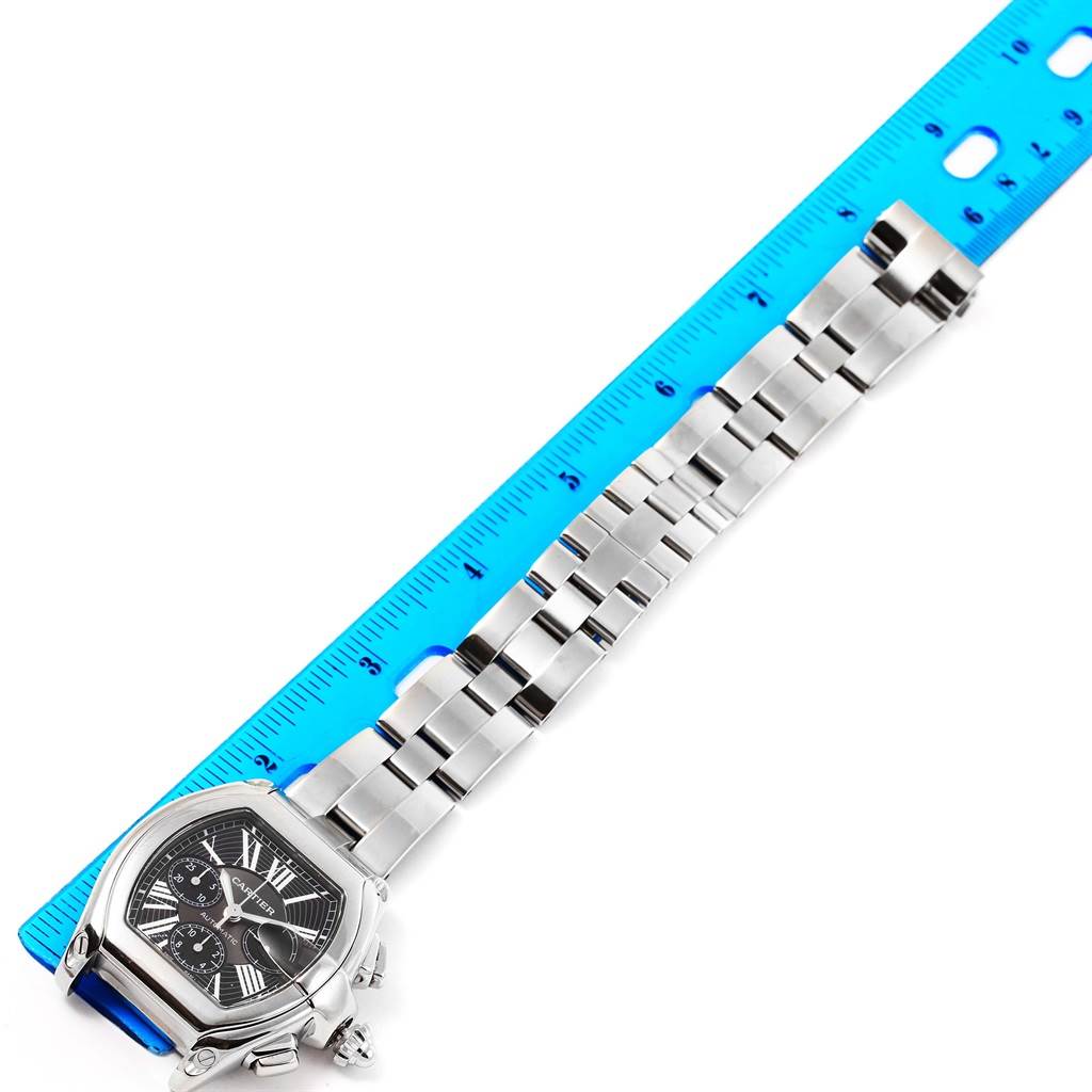The image shows a Cartier Roadster W62020X6 Men
s Stainless Steel Black Dial W62020X6 Men
s Stainless Steel Black Dial watch with a bracelet measured against a blue ruler, viewed from above.