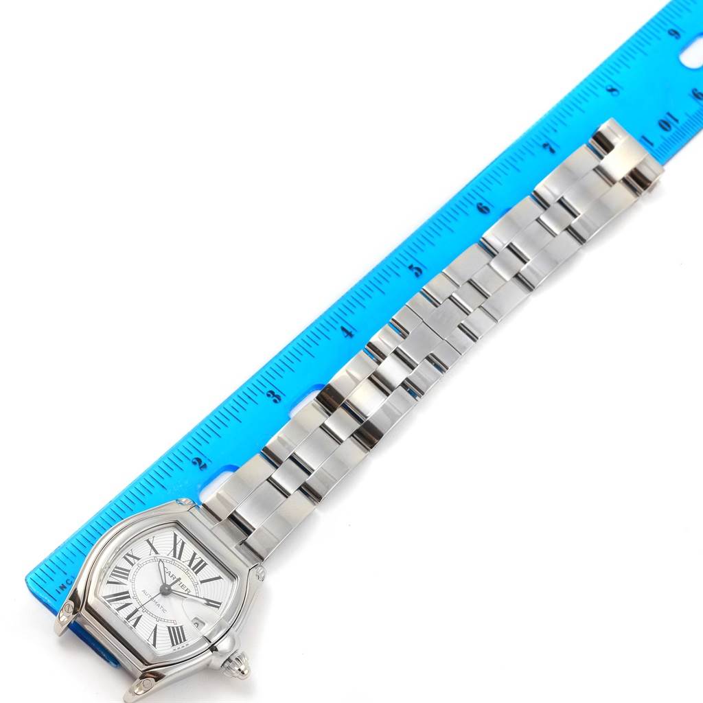 The Cartier Roadster W62025V3 Men's Stainless Steel Silver Dial W62025V3 Men's Stainless Steel Silver Dial watch is shown from the top, displaying its face and full metal band against a blue ruler.