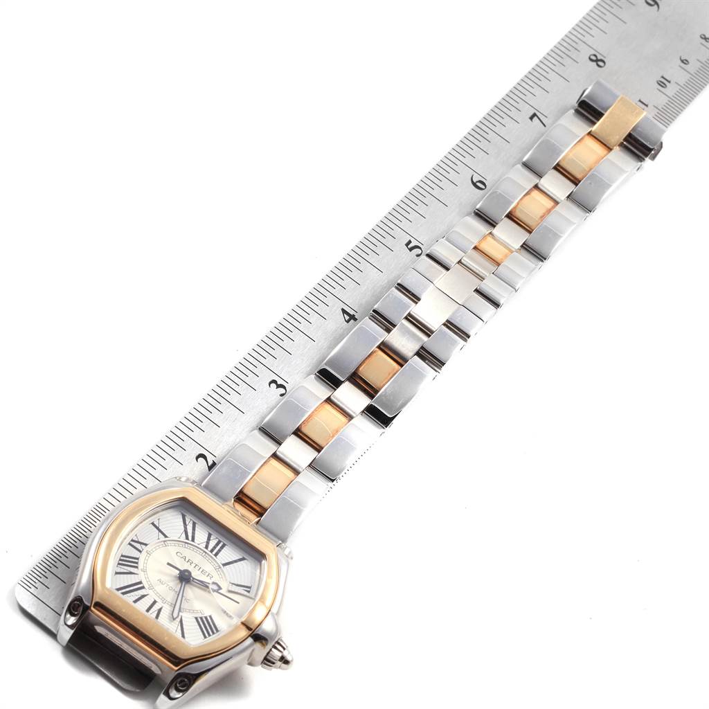 The image shows a Cartier Roadster W62031Y4 Men's Steel and Gold (two tone) Silver Dial W62031Y4 Men's Steel and Gold (two tone) Silver Dial watch laid flat alongside a ruler, highlighting its two-tone metal bracelet.