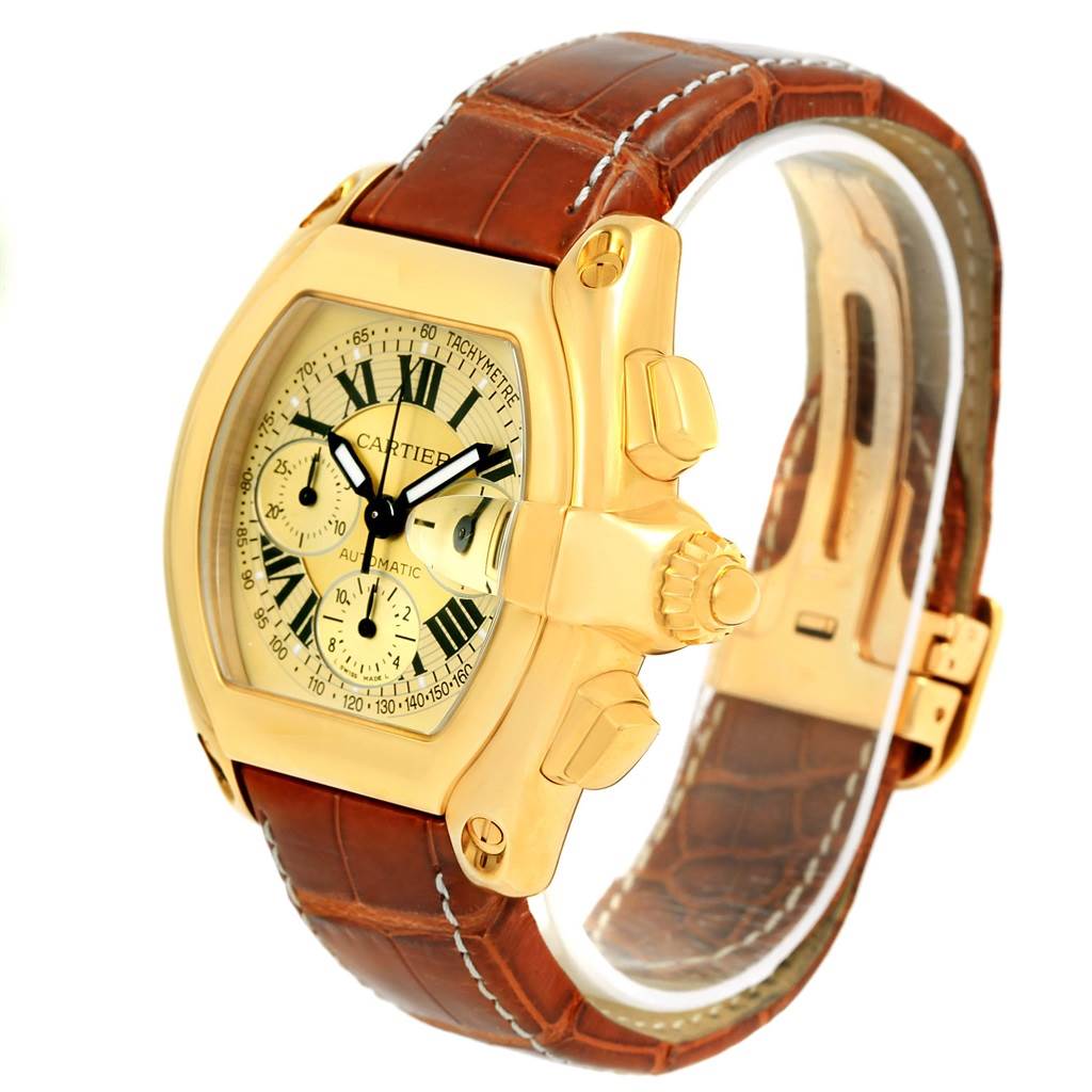 The Cartier Roadster W62021Y3 Men
s Yellow Gold Champagne Dial W62021Y3 Men
s Yellow Gold Champagne Dial watch is shown at a slight angle, highlighting its face, crown, and brown leather strap.