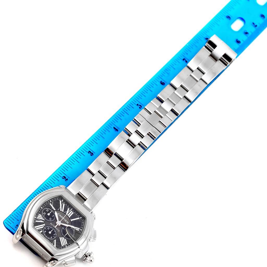 This image shows a Cartier Roadster W62020X6 Men's Stainless Steel Black Dial W62020X6 Men's Stainless Steel Black Dial watch laid flat next to a blue ruler, displaying its band and dial face from above.