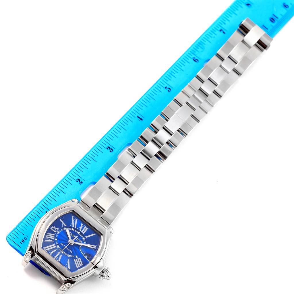 The Cartier Roadster W62048V3 Men
s Stainless Steel Blue Dial W62048V3 Men
s Stainless Steel Blue Dial watch is shown from a top-down angle, displaying its face, strap, and a blue measuring ruler.