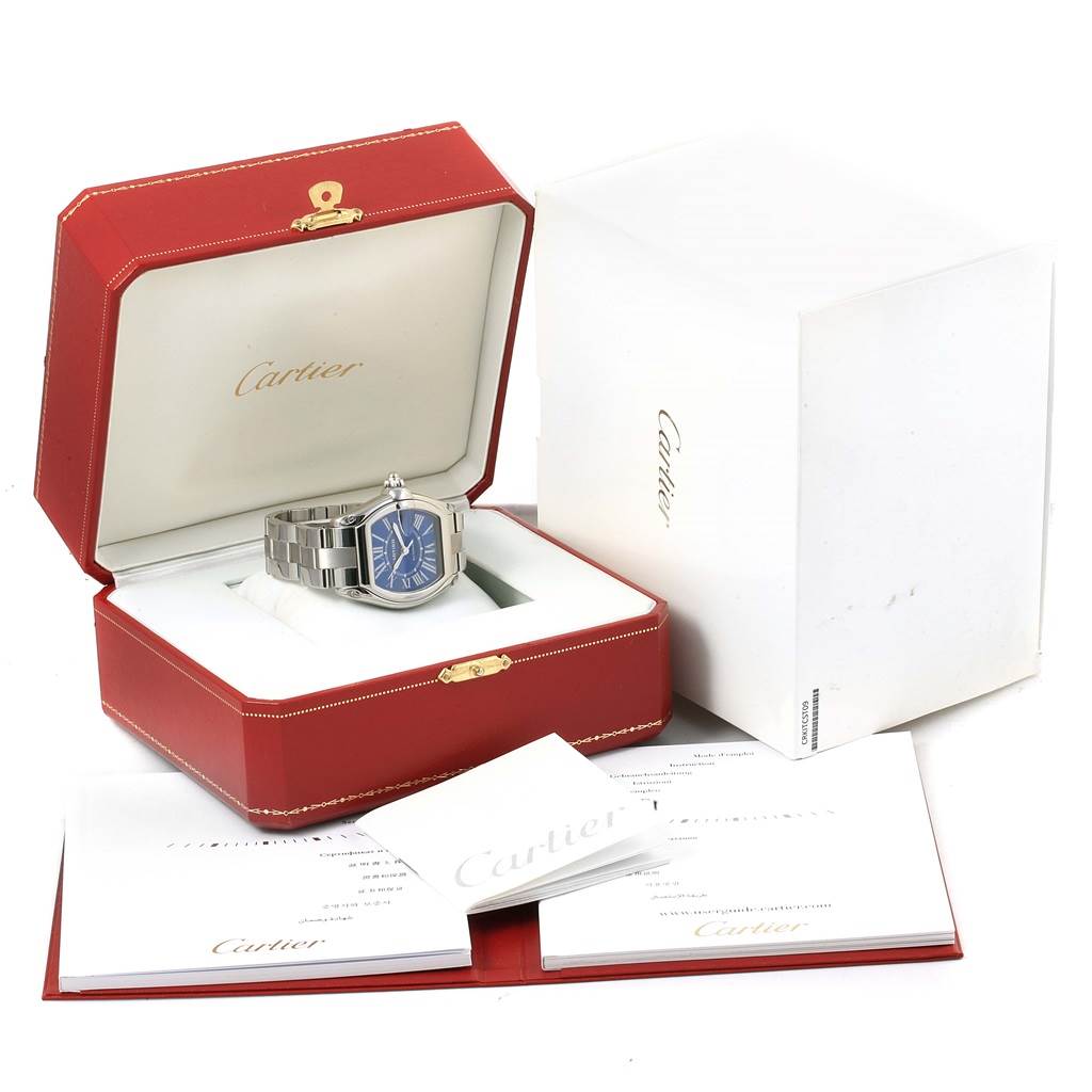 The Cartier Roadster W62048V3 Men's Stainless Steel Blue Dial W62048V3 Men's Stainless Steel Blue Dial watch is shown in an open red box with additional packaging and booklets around it.