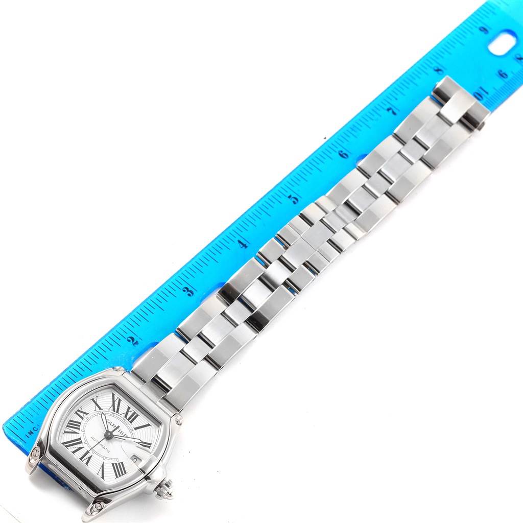 The Cartier Roadster W62025V3 Men's Stainless Steel Silver Dial W62025V3 Men's Stainless Steel Silver Dial watch is shown from a top-down angle, displaying the face, bezel, and entire bracelet next to a ruler.