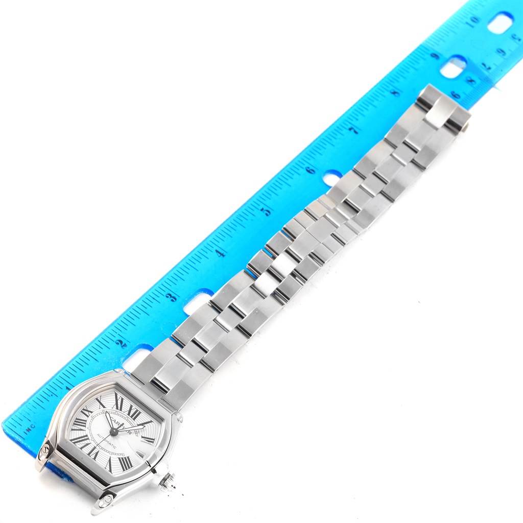 The Cartier Roadster W62025V3 Men's Stainless Steel Silver Dial W62025V3 Men's Stainless Steel Silver Dial watch is shown lying flat with a blue ruler beside it, displaying the face and the metal band.