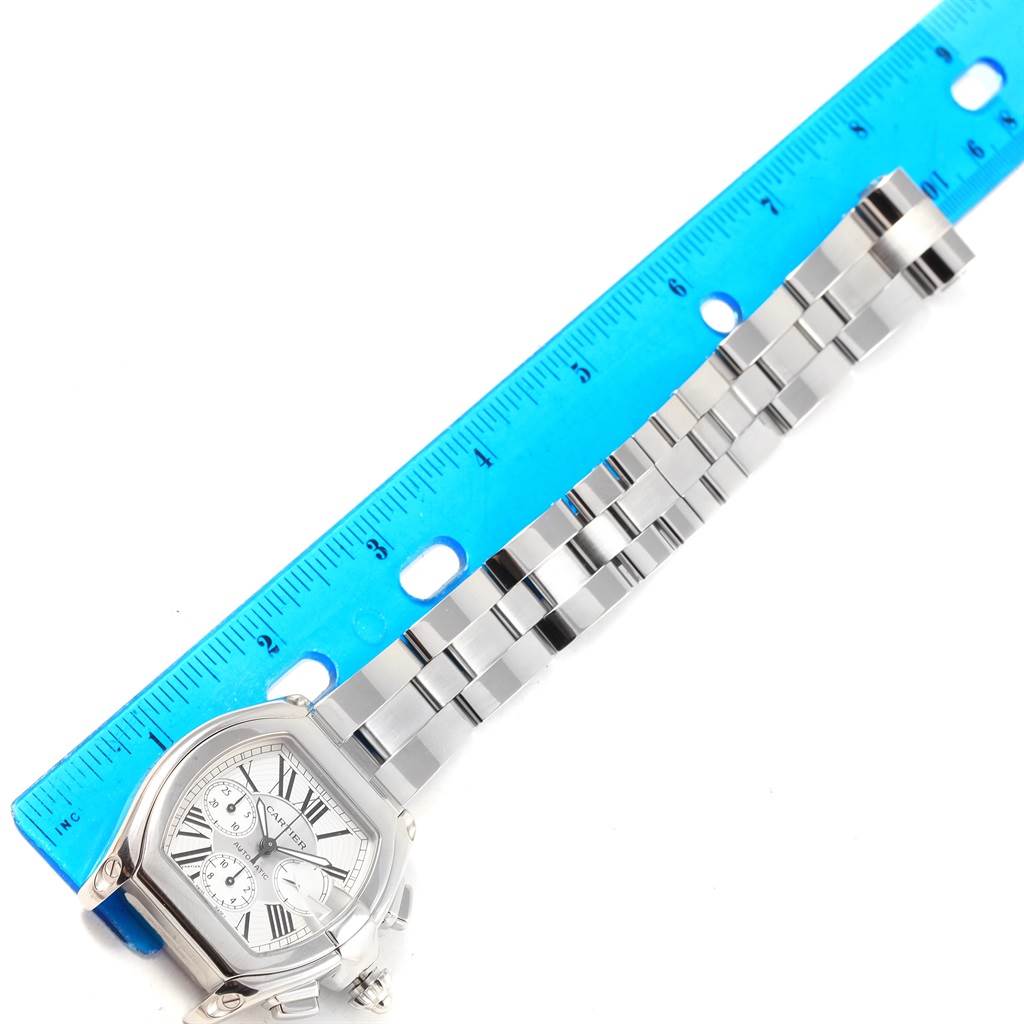 This image shows a Cartier Roadster W62019X6 Men's Stainless Steel Silver Dial W62019X6 Men's Stainless Steel Silver Dial watch with its face and metal bracelet, alongside a blue ruler for scale.