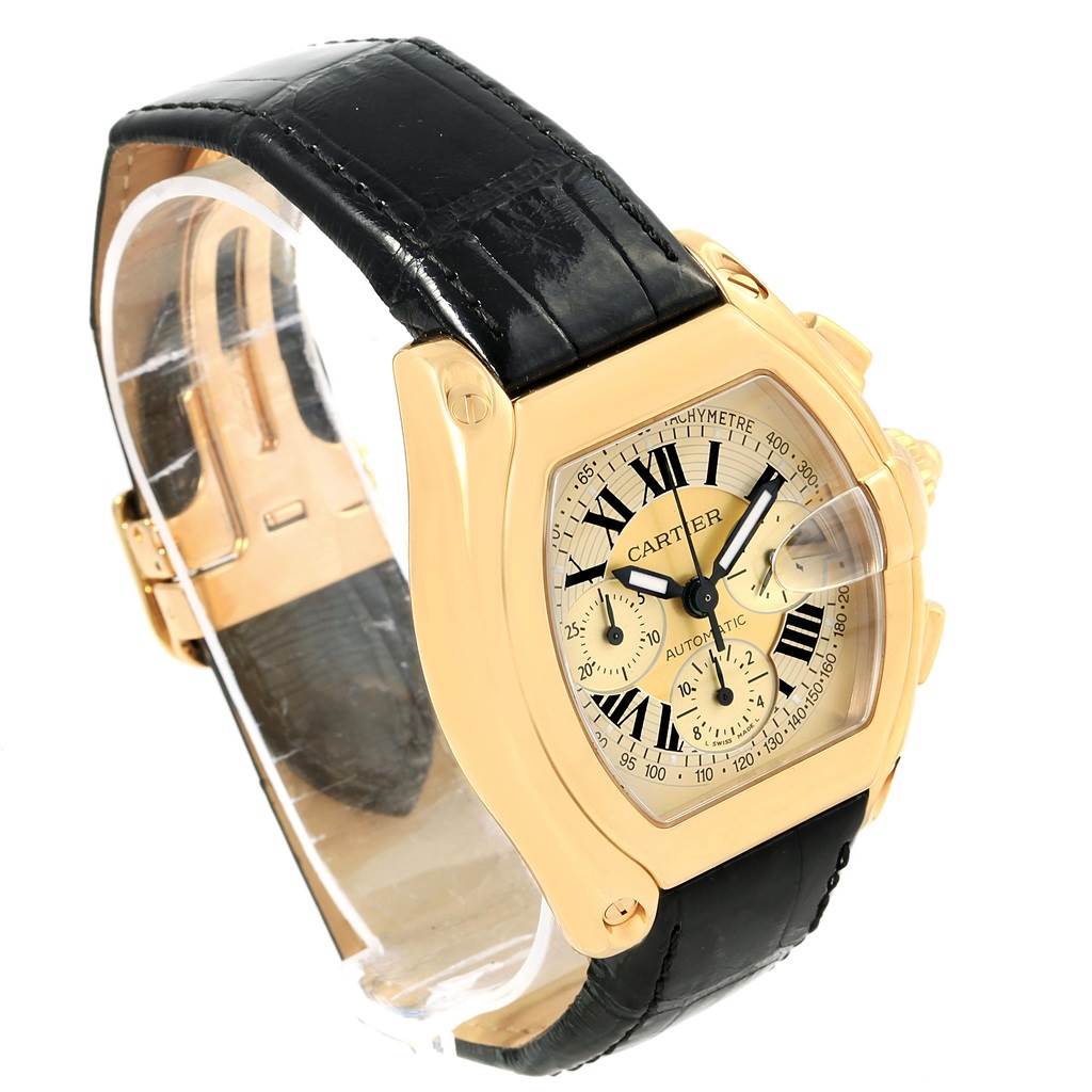 The image shows a Cartier Roadster W62021Y3 Men's Yellow Gold Champagne Dial W62021Y3 Men's Yellow Gold Champagne Dial watch from a slight angle, highlighting its gold case, black leather strap, and detailed dial.