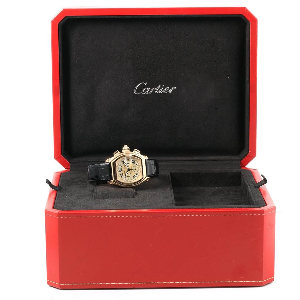 The Cartier Roadster W62021Y3 Men's Yellow Gold Champagne Dial W62021Y3 Men's Yellow Gold Champagne Dial watch is showcased in its red display box, with parts including the face, bezel, and strap visible.