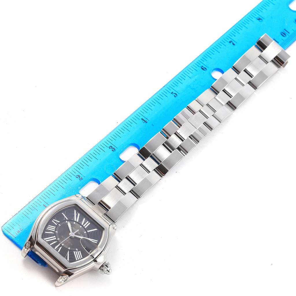 This image shows a top view of a Cartier Roadster W62041V3 Men
s Stainless Steel Black Dial W62041V3 Men
s Stainless Steel Black Dial watch with its metal bracelet next to a blue ruler.