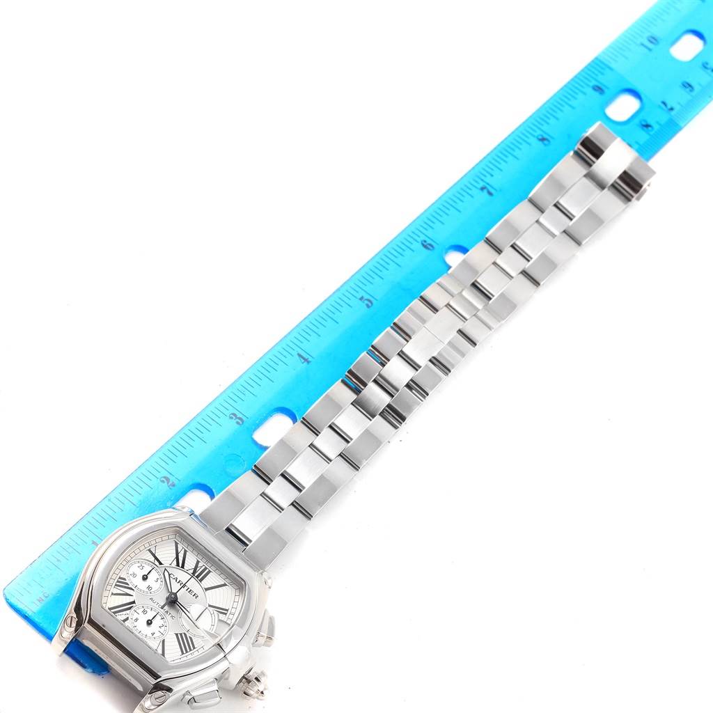 The Cartier Roadster W62019X6 Men's Stainless Steel Silver Dial W62019X6 Men's Stainless Steel Silver Dial watch is shown from a top-down angle, focusing on the face and metal bracelet with a ruler for scale.