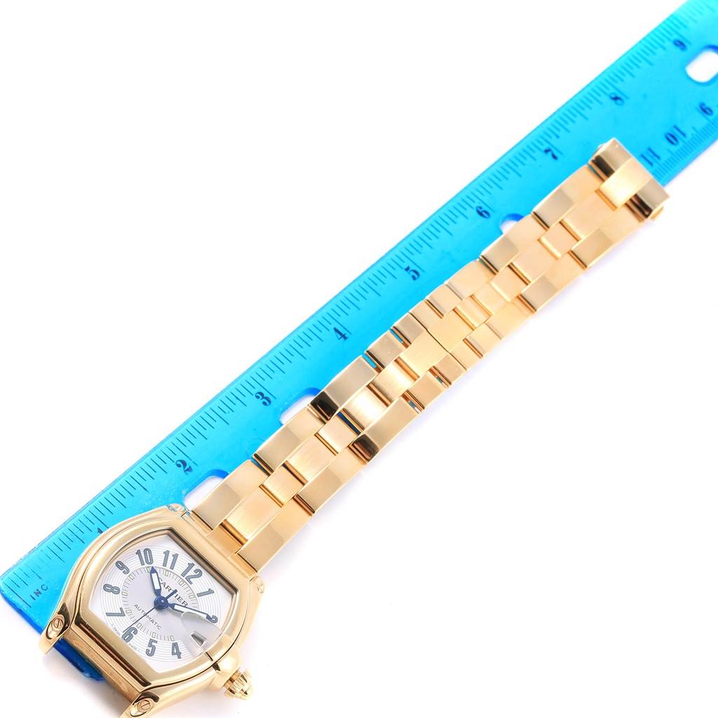 The Cartier Roadster W62005V1 Men's Yellow Gold Silver Dial W62005V1 Men's Yellow Gold Silver Dial watch is displayed flat with its face and full bracelet visible alongside a blue ruler.