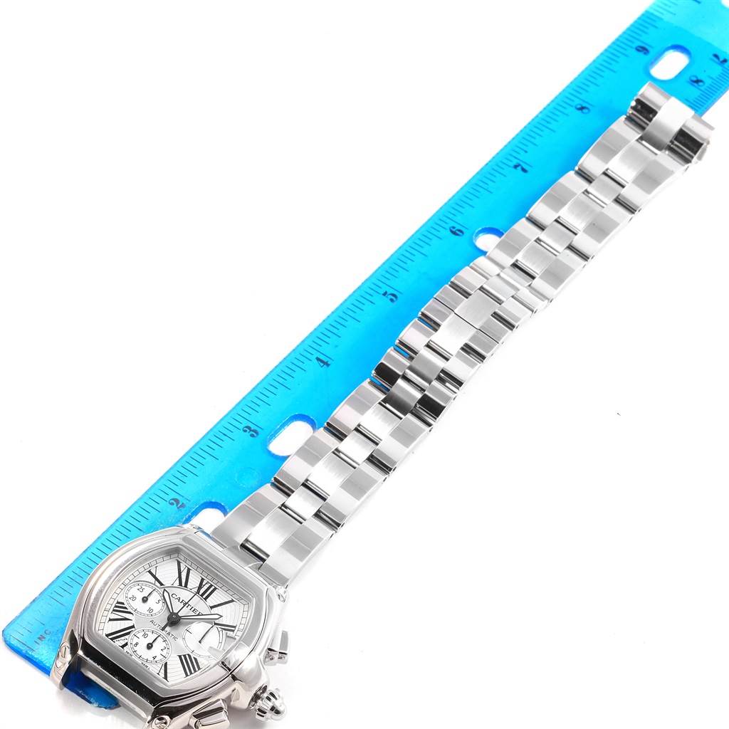 The image shows the Cartier Roadster W62019X6 Men
s Stainless Steel Silver Dial W62019X6 Men
s Stainless Steel Silver Dial watch laid flat with its stainless steel band extended alongside a measuring ruler.