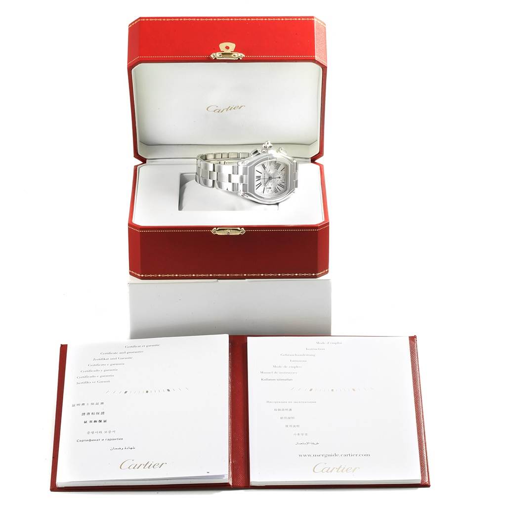 The Cartier Roadster W62019X6 Men
s Stainless Steel Silver Dial W62019X6 Men
s Stainless Steel Silver Dial watch is shown in its open red case, with warranty booklets displayed in front.