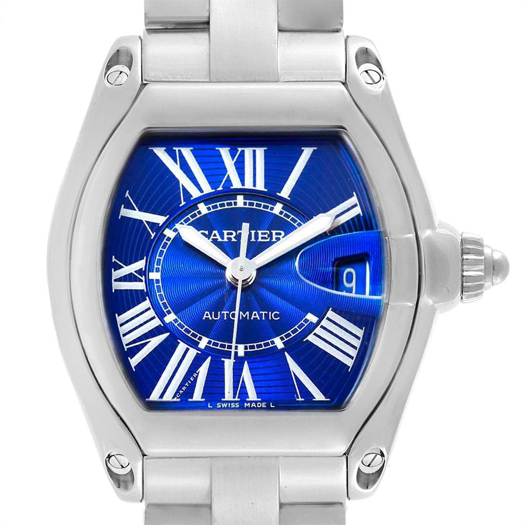 The image shows a close-up of the Cartier Roadster W62048V3 Men's Stainless Steel Blue Dial W62048V3 Men's Stainless Steel Blue Dial watch face, highlighting its blue dial, Roman numerals, and stainless steel case and bracelet.