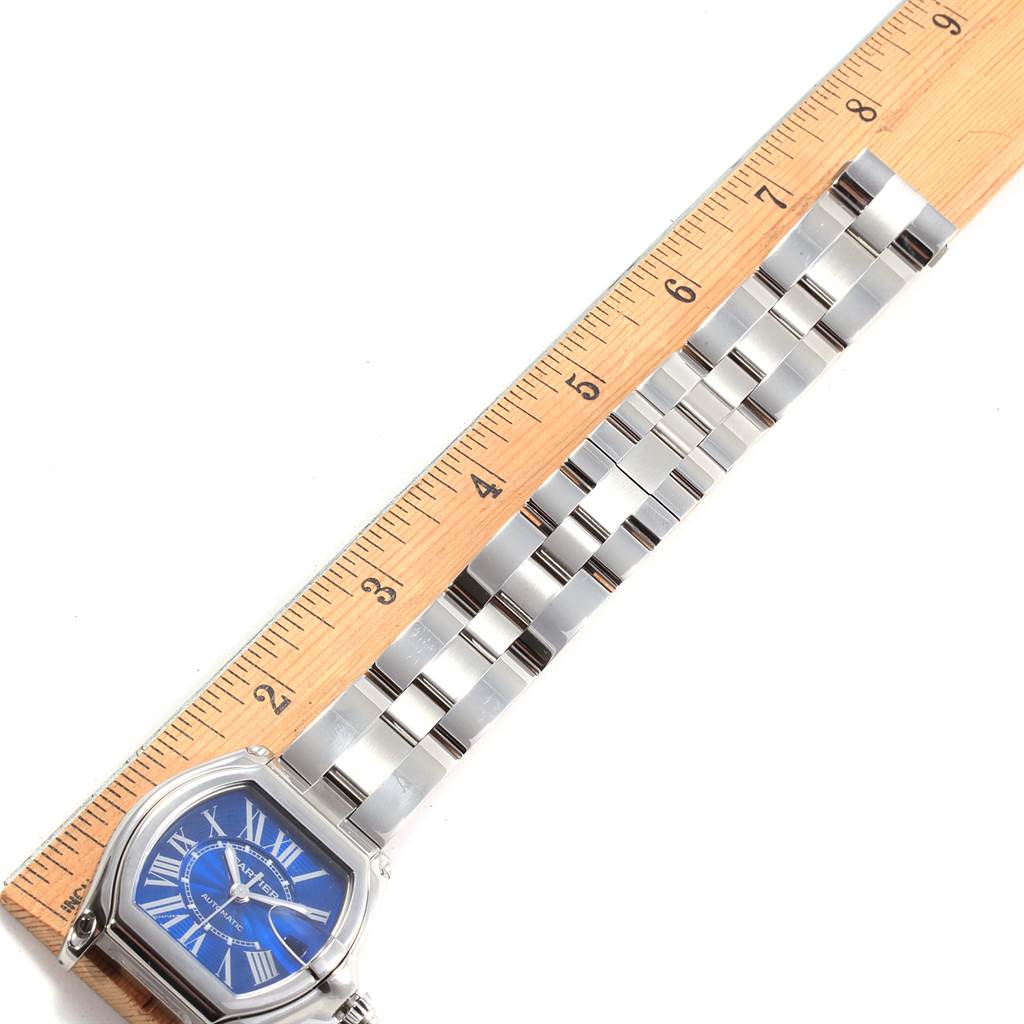 The image shows a Cartier Roadster W62048V3 Men's Stainless Steel Blue Dial W62048V3 Men's Stainless Steel Blue Dial watch face and part of the metal bracelet alongside a measuring ruler.