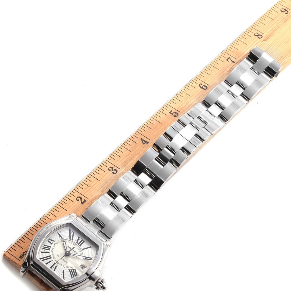 The image shows a Cartier Roadster W62025V3 Men
s Stainless Steel Silver Dial W62025V3 Men
s Stainless Steel Silver Dial watch laid flat against a ruler, displayed from the face to the end of the bracelet.