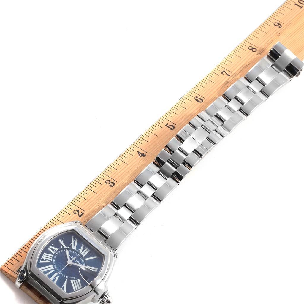 The image shows a Cartier Roadster W6206012 Men
s Stainless Steel Blue Dial W6206012 Men
s Stainless Steel Blue Dial watch laid against a ruler, displaying its face and bracelet from an overhead angle.