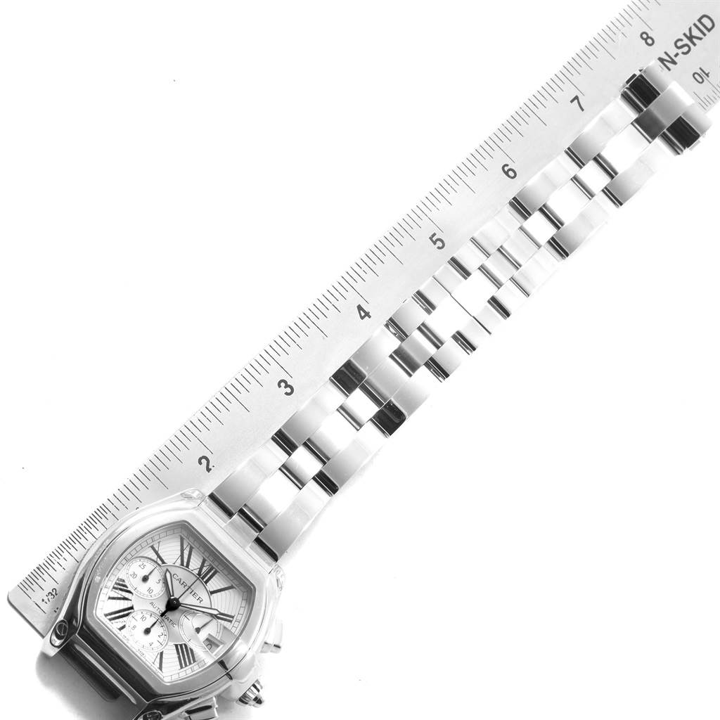 The image shows a Cartier Roadster W62019X6 Men's Stainless Steel Silver Dial W62019X6 Men's Stainless Steel Silver Dial watch at an angle, displaying the face, bezel, and part of the metal bracelet alongside a ruler.