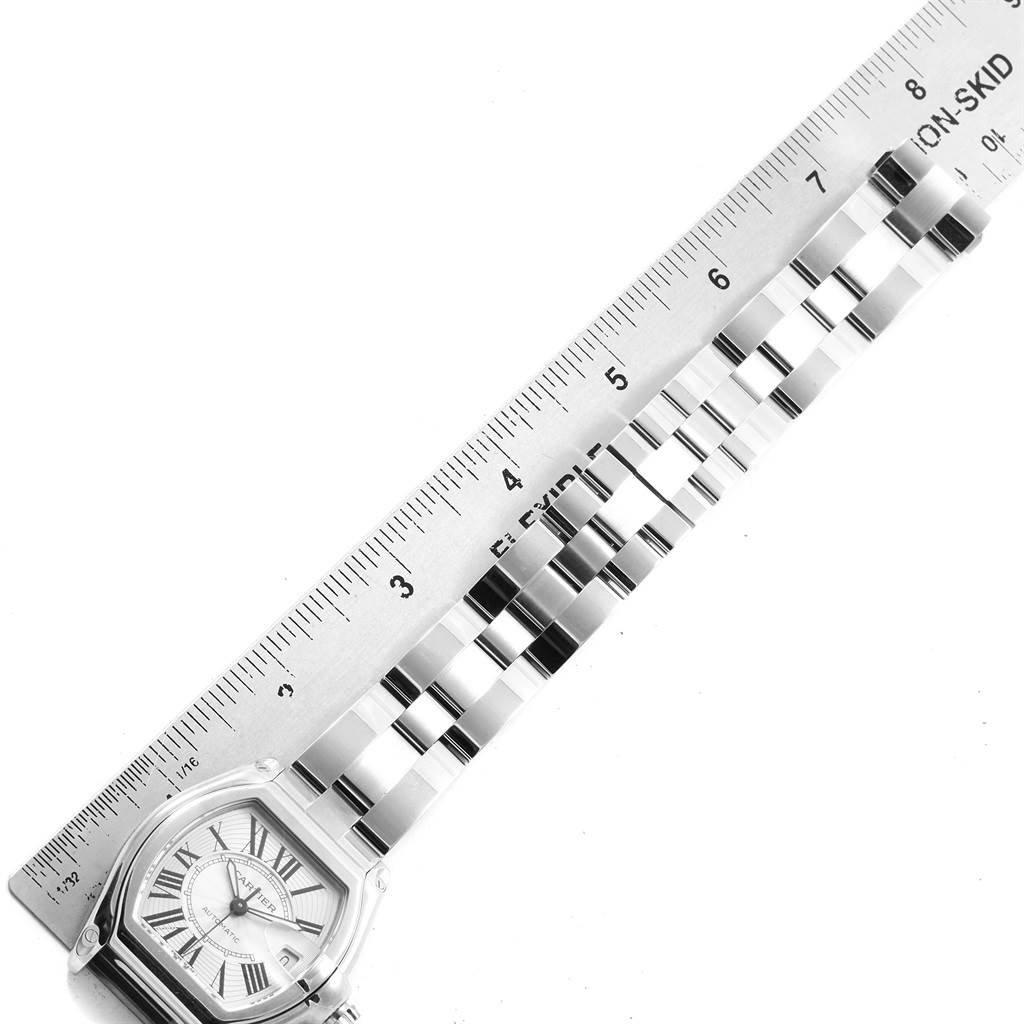 The image shows a close-up of the Cartier Roadster W62025V3 Men
s Stainless Steel Silver Dial W62025V3 Men
s Stainless Steel Silver Dial watch face and part of the metal bracelet next to a ruler.