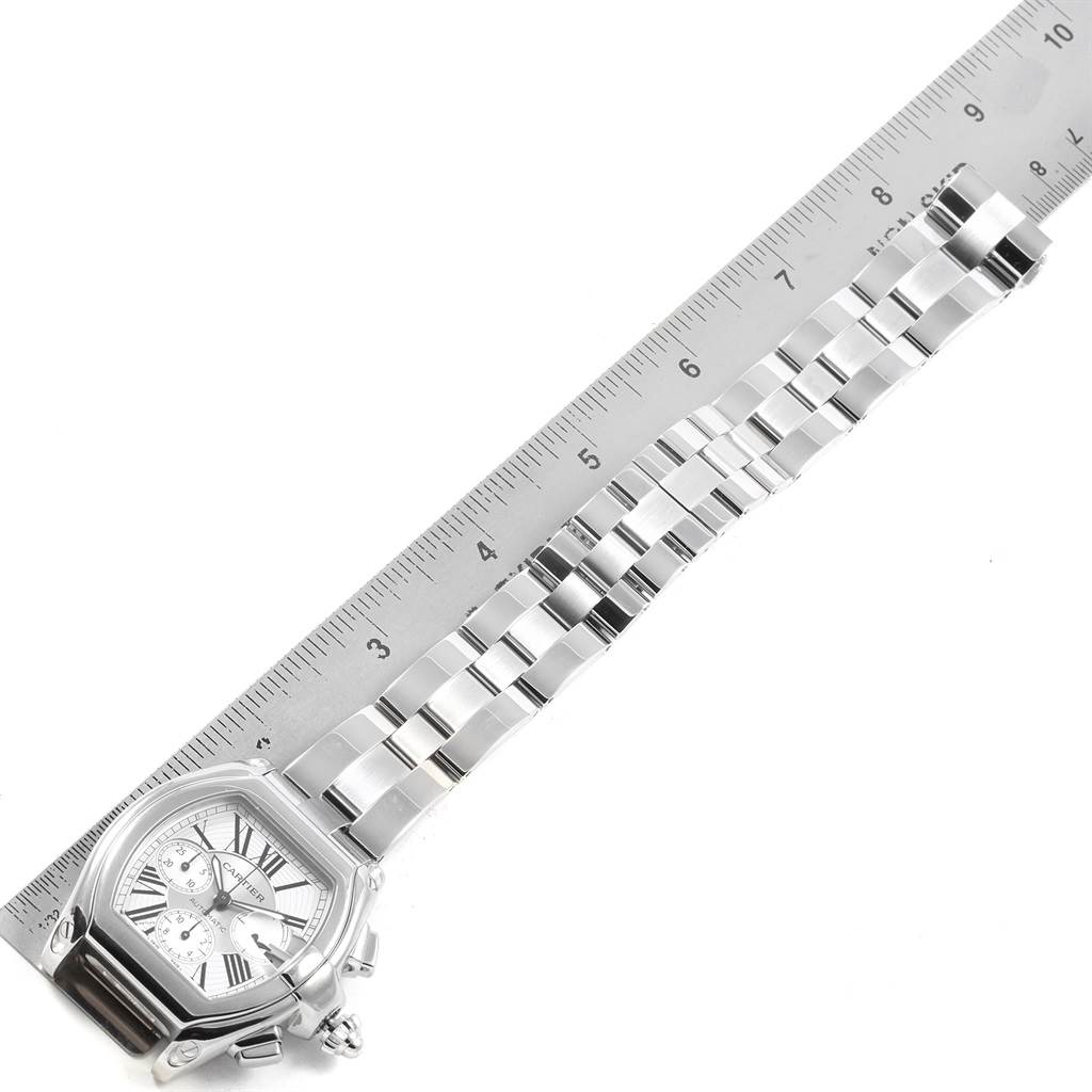 The image displays a Cartier Roadster W62019X6 Men
s Stainless Steel Silver Dial W62019X6 Men
s Stainless Steel Silver Dial watch from a top-down angle, showcasing the watch face, bracelet, and a ruler for scale.